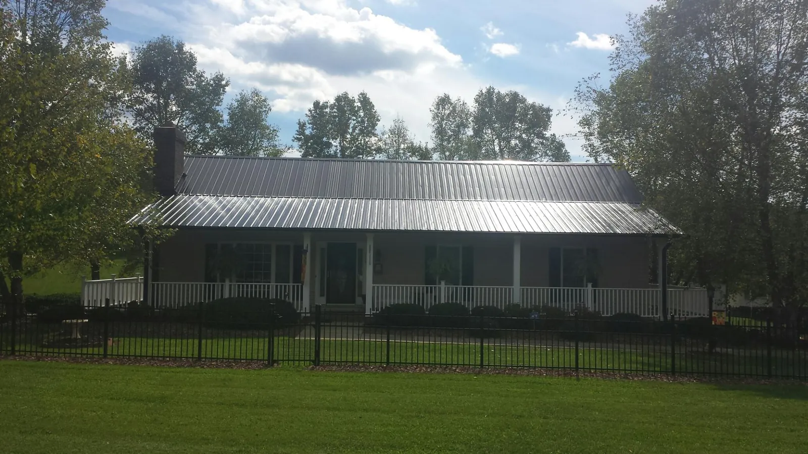 Gray metal roof on a brick ranch with a full width front porch — Gutter Guard Installation work by our crew in Ward